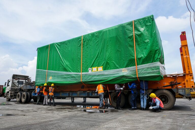 A tiny house being loaded onto a trailer by a team of professionals
